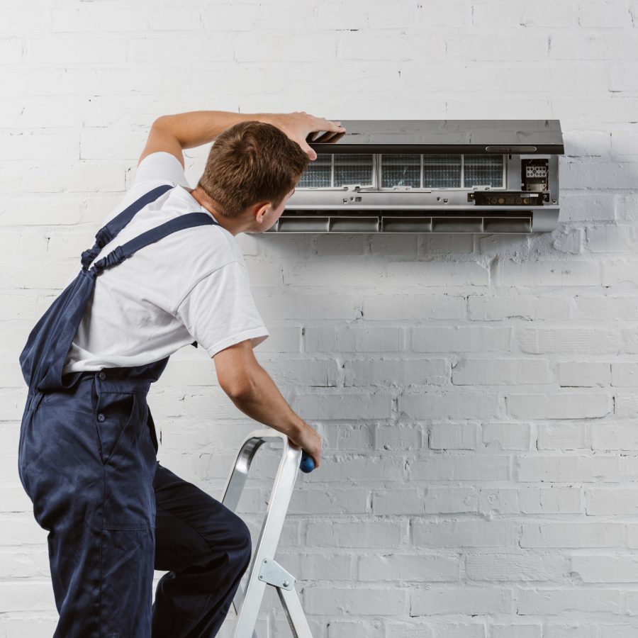 rear view of air conditioner repairman standing on stepladder